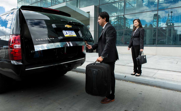 Пара загружает багаж в черную машину