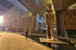 Statue of a sphinx in a modern architectural setting with people walking around.