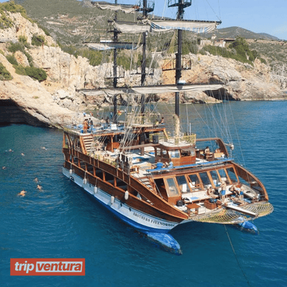 A spacious catamaran boat cruising on Alanya's turquoise waters under a sunny sky, surrounded by scenic views