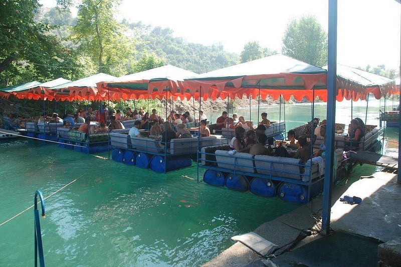 Poeple having lunch in huts built over a river