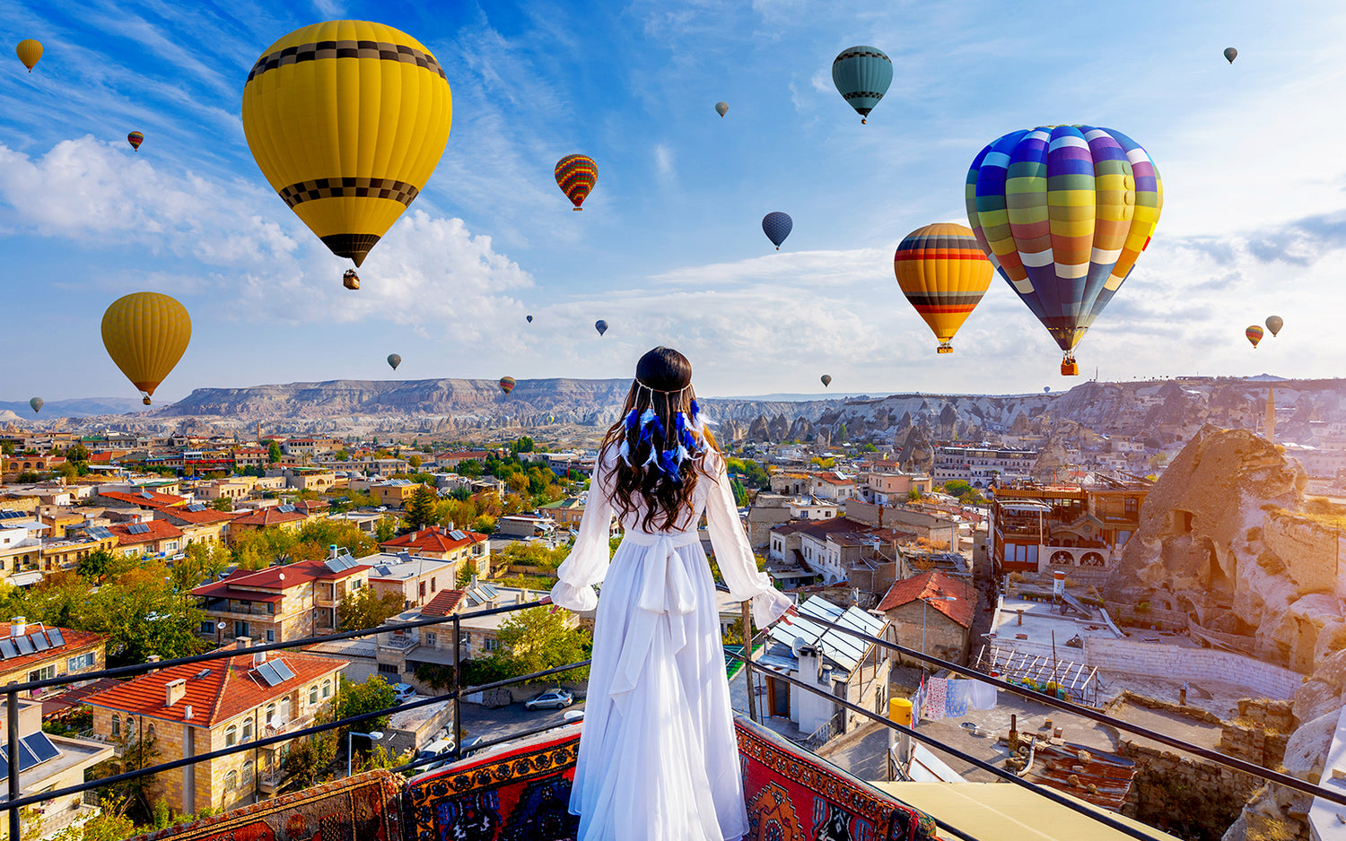 Stunning view of Cappadocia's unique rock formations, fairy chimneys, and cave dwellings, with hot air balloons floating in the sky.