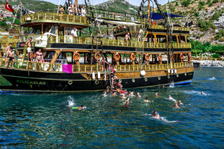 People swiming in the ocean along with the pirate boat