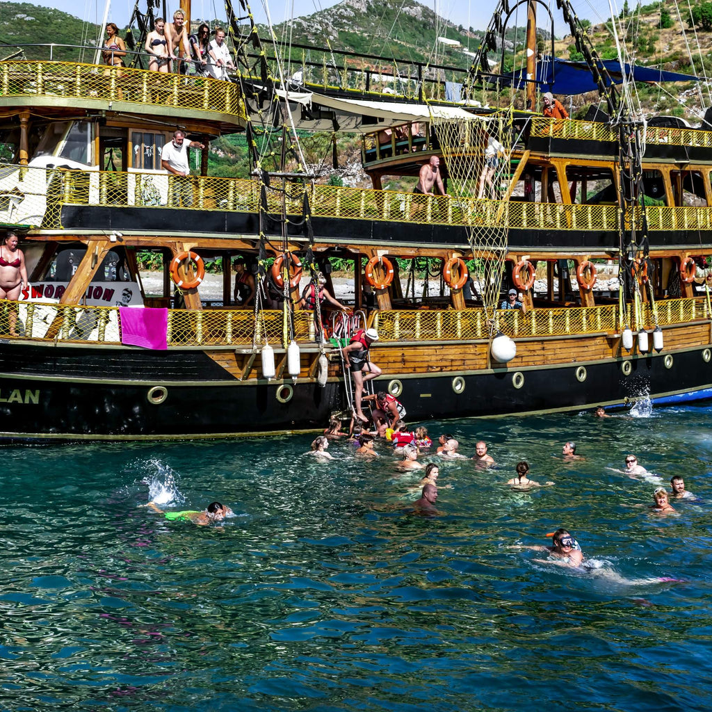 Korsan teknesiyle birlikte okyanusta yüzen insanlar