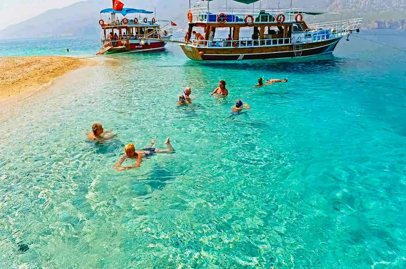Gäste schwimmen im kristallklaren Wasser von Suluada.