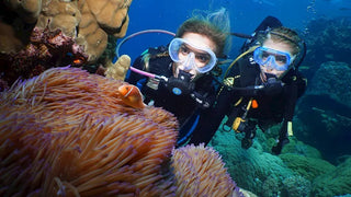Girls scuba diving and exploring coral reefs