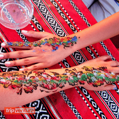 Artist applying intricate henna designs on a guest’s hand at the camp.