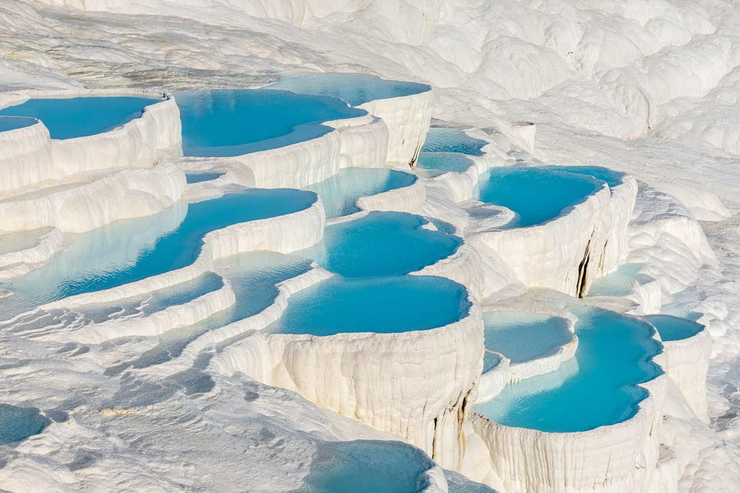 he unique white travertine terraces of Pamukkale with ancient ruins in the background, showcasing Turkey's rich cultural and natural heritage.