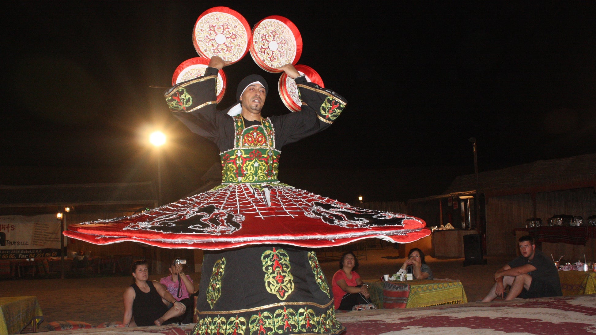 Tanoura dancer spinning in vibrant illuminated skirts during the evening entertainment.