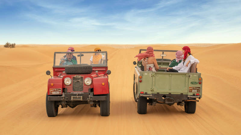 En klassisk vintage Land Rover kører gennem Dubais gyldne ørkensand.